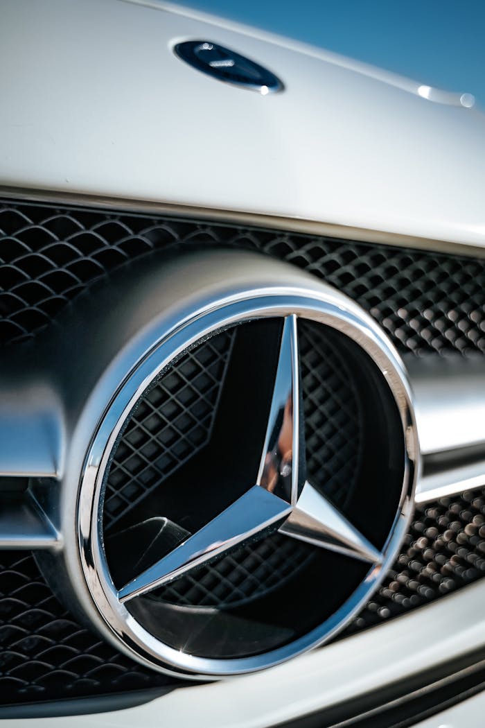 Detailed shot of a gleaming Mercedes Benz logo on a car grille.