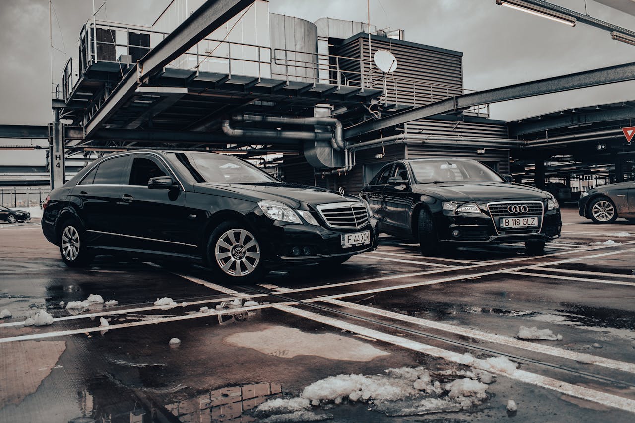Two black luxury cars parked in a winter industrial setting showcasing elegance and modern design.