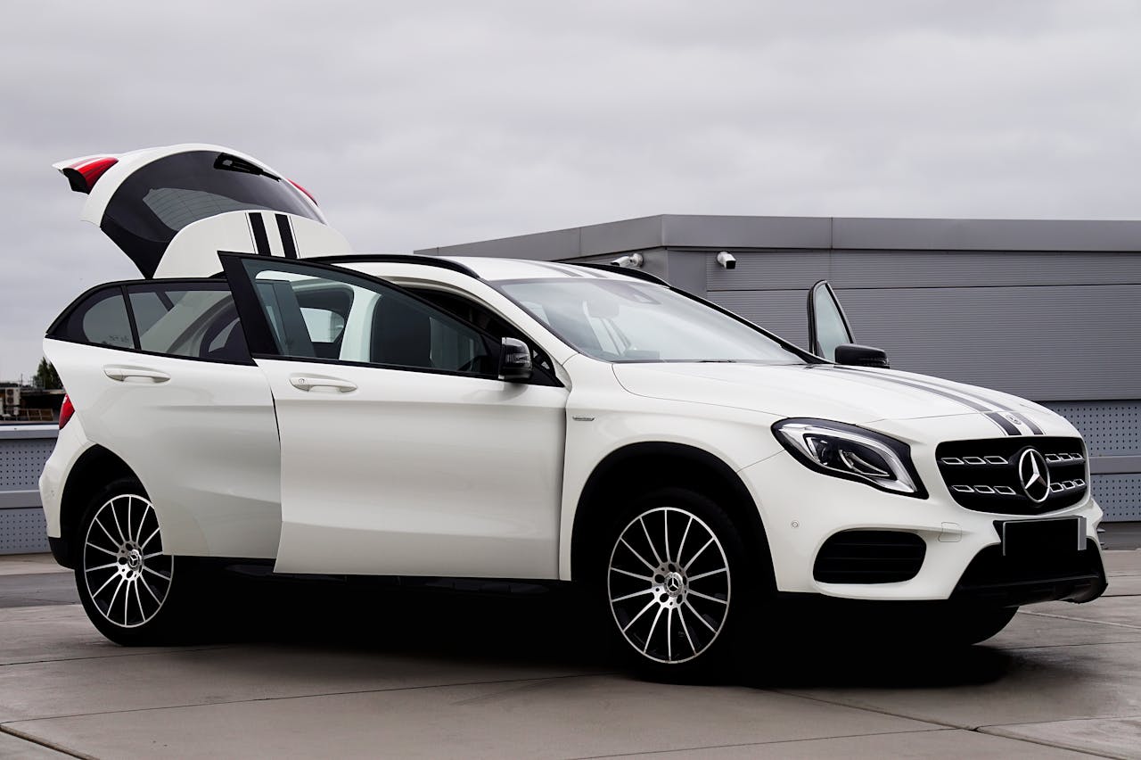 Stylish white Mercedes-Benz SUV with open doors on a rooftop parking area.